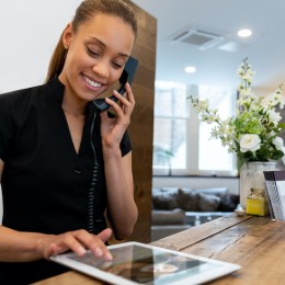 Woman working at a spa talking on the phone and making a booking