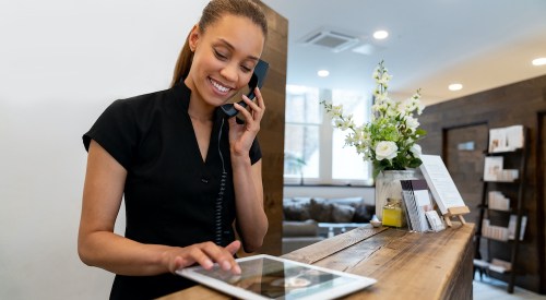 Woman working at a spa talking on the phone and making a booking