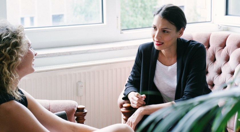 Office scene, two businesswomen. Informal coaching session on the sofa.